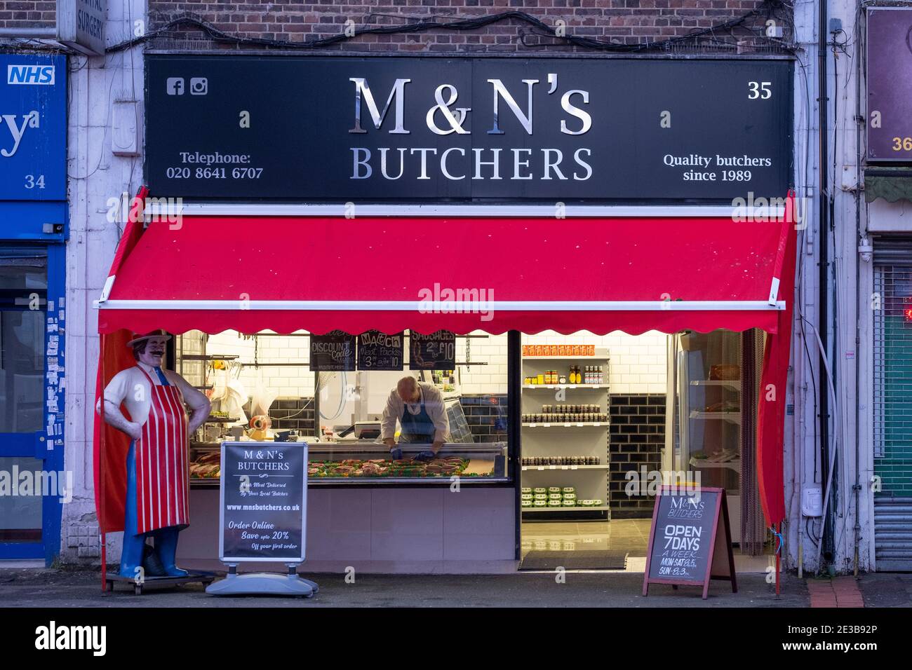 Sutton, Surrey, UK. 18 January 2021. A local butcher prepares his window display in the early morning. During the current lockdown he is open and trading 7 days a week as an exempt occupation. Credit: Malcolm Park/Alamy Live News. Stock Photo