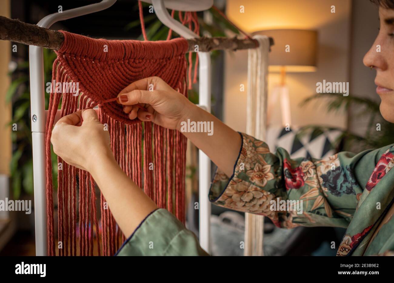 A woman working on a macrame wall hanger at home during the lock down Stock Photo