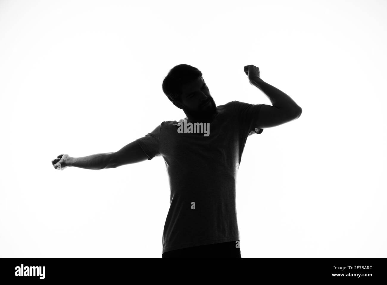 black silhouette of a man who gestures with his hands on a light ...