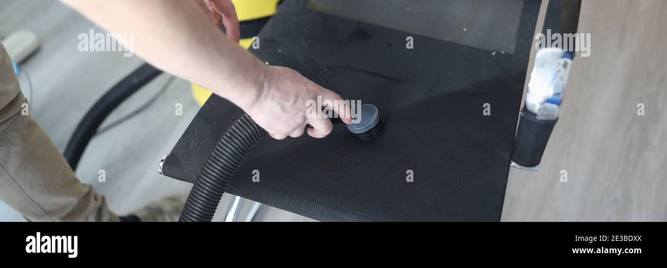 Man clean dust from chair by vacuum cleaner. Stock Photo