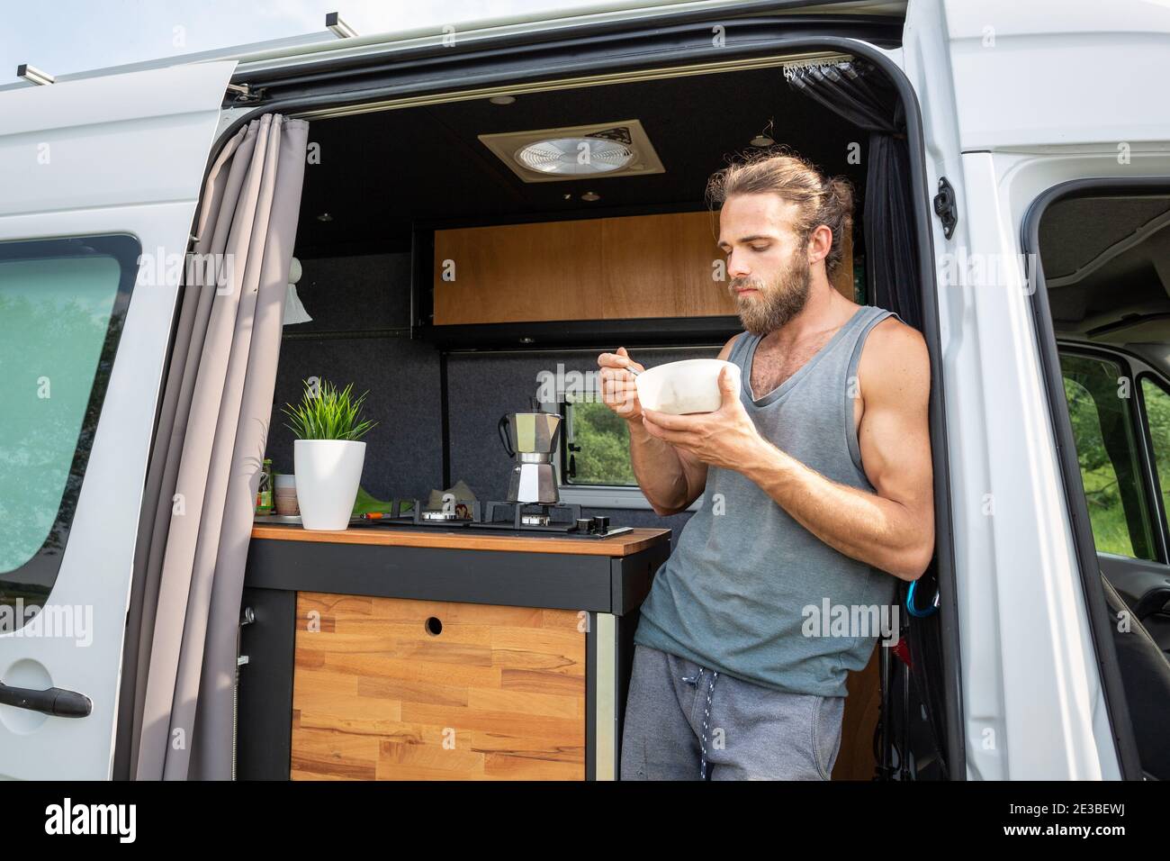 Man having breakfast in the door of his camper van Stock Photo