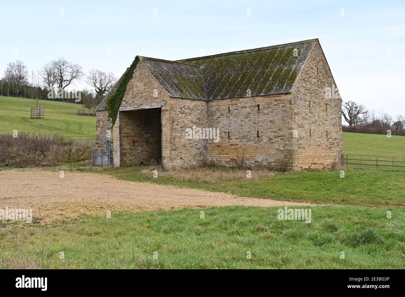 A farm barn stands by a field in the north Oxfordshire hamlet of Little Rollright. The hamlet is a privately owned estate formerly owned by Oxford Uni Stock Photo