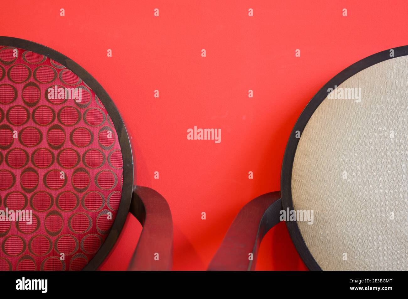 Abstract Minimalist Detail of Modern Dining Chairs with Round Chair-Backs Photographed Against a Red Wall Stock Photo