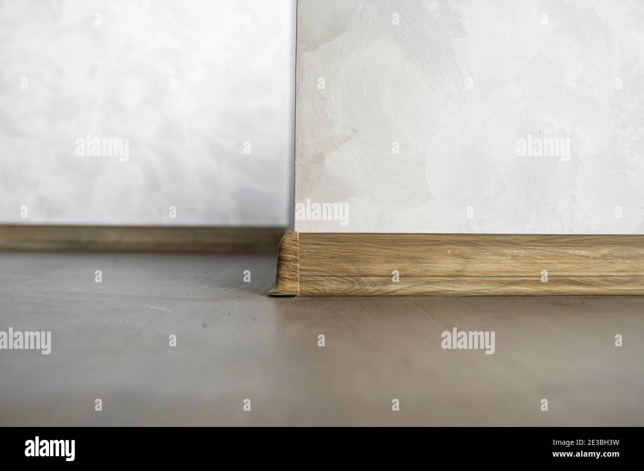 Laminate with plastic baseboard with a wooden texture. Newly installed wooden laminate flooring