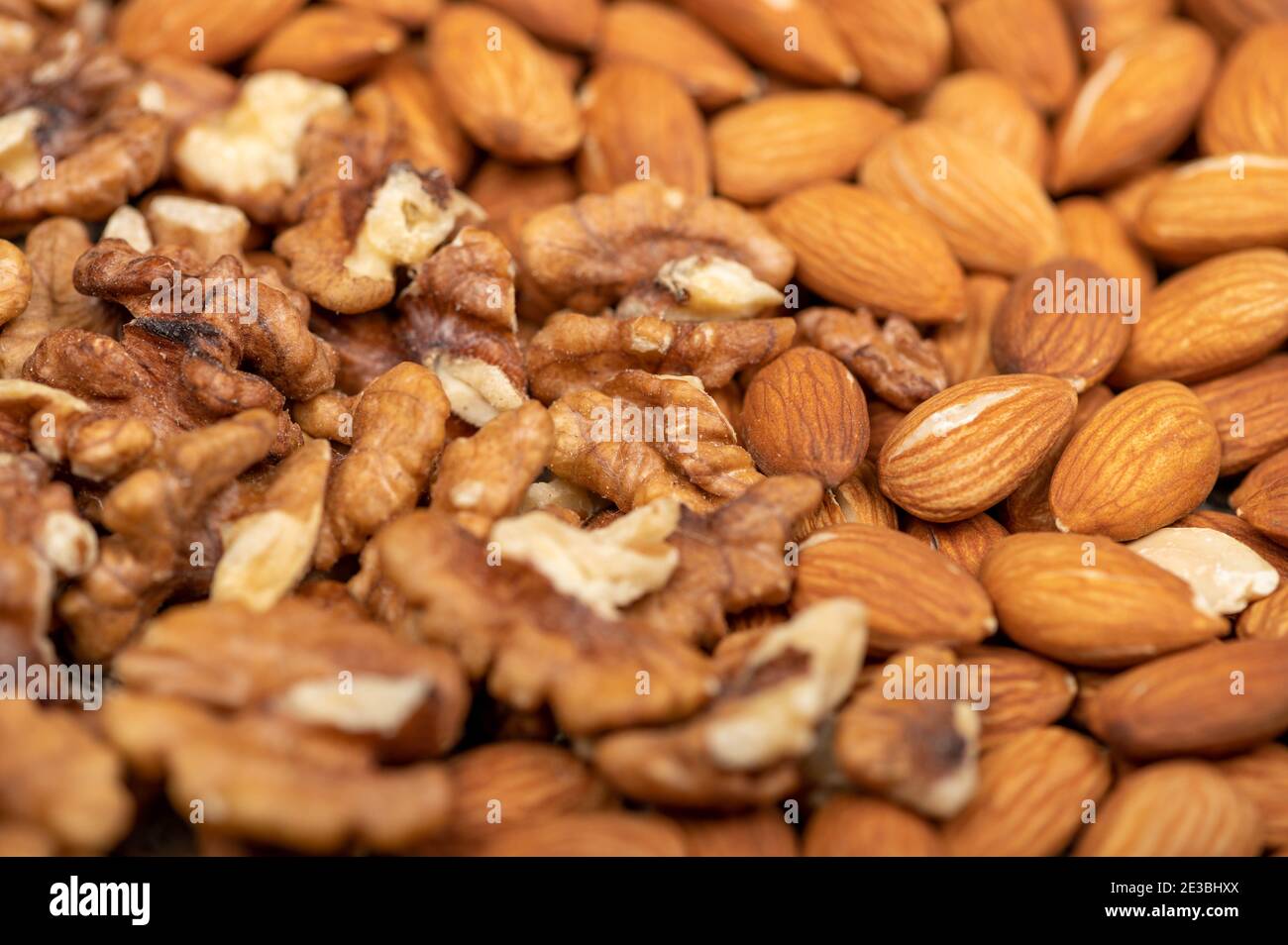 Almonds and walnuts scattered on the table. Close-up, selective focus Stock Photo