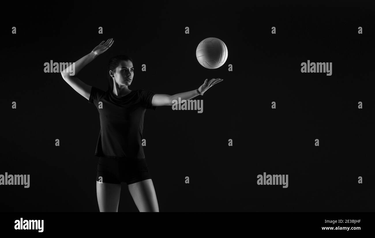 Volleyball girl hold and kick ball on dark background. Player doing sport workout online