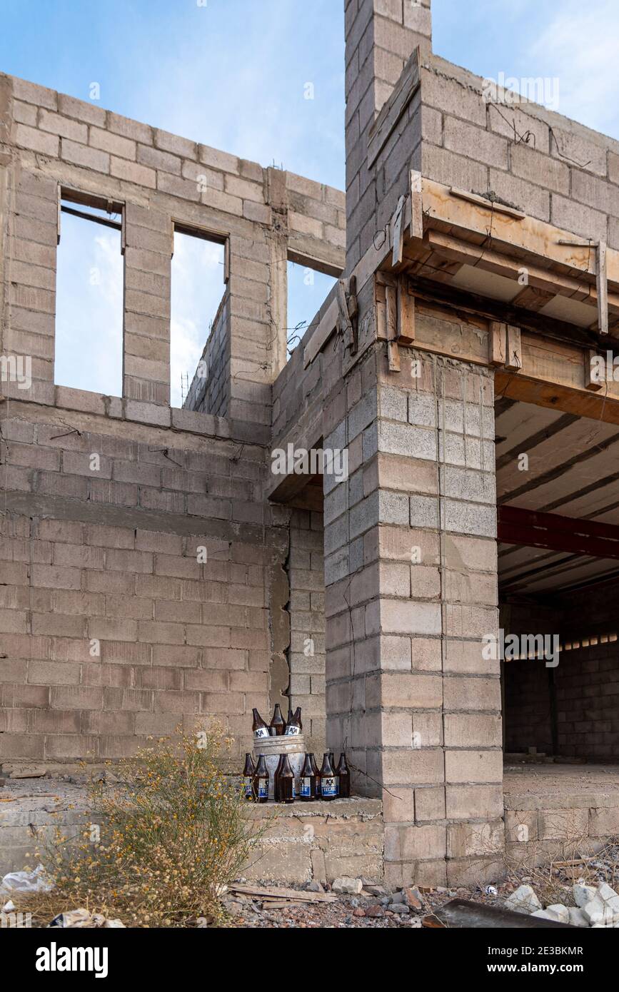 Beer bottles stacked in and around a white five-gallon bucket on a construction site. Stock Photo