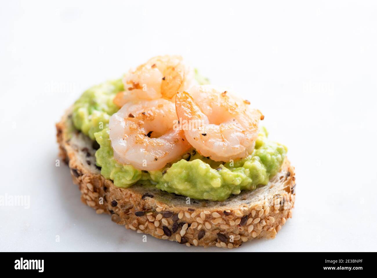 Appetizer toast or bruschetta with avocado cream and shrimps isolated on white marble background Stock Photo