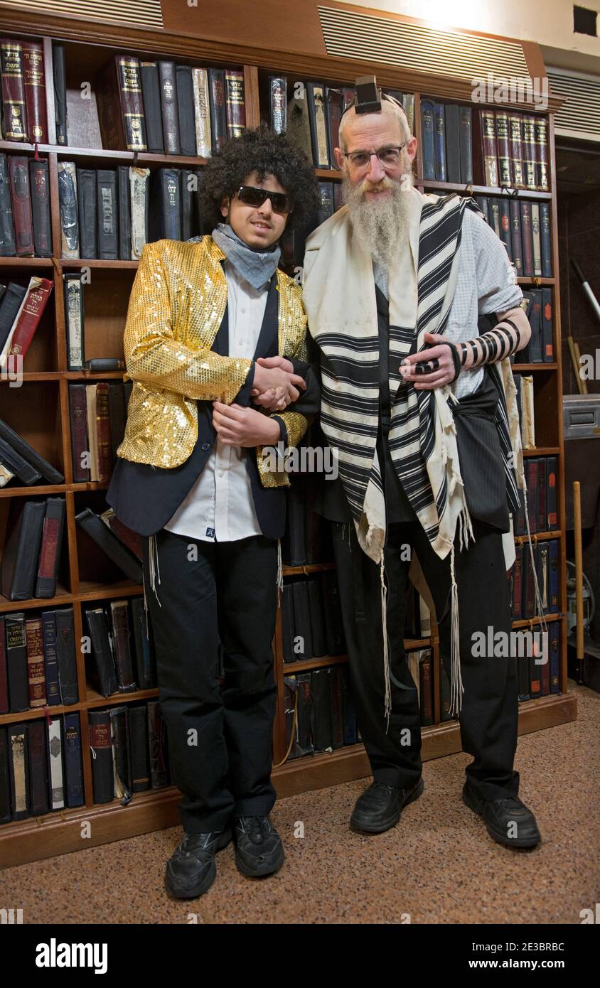 On the festive holiday of Purim where costumes are a tradition, 2 Jewish men of different age groups shake hands. In Crown Heights, Brooklyn, New York. Stock Photo