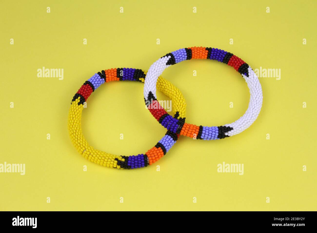 Colourful African beaded bangles against a bright yellow background. Stock Photo