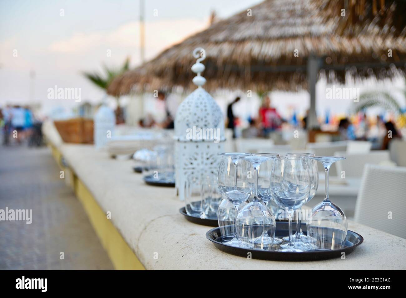 Wine glasses on a tray. Decorative candlestick on pier at restaurant on beach in Italy Stock Photo