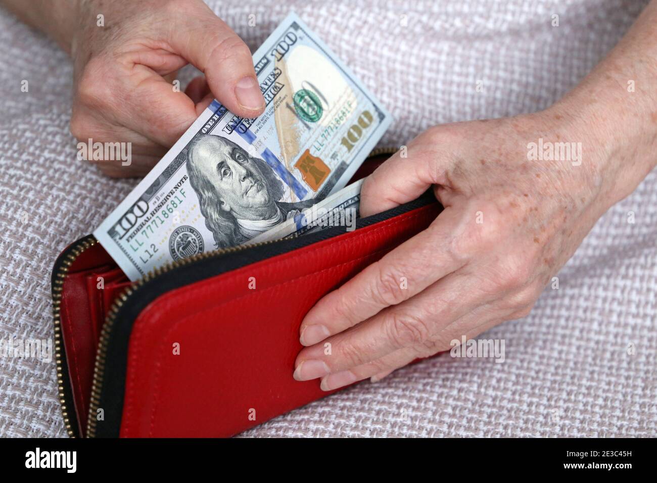 Elderly woman takes out US dollars from her wallet. Concept of pension payments, savings at retirement, pensioner with money Stock Photo