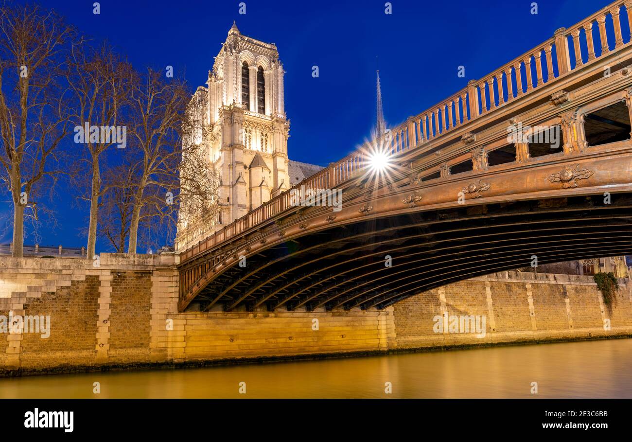 Evening view of the Notre Dame Cathedral and Pont Au Double, Paris France, during the winter from the embankment of the Seine River. Stock Photo