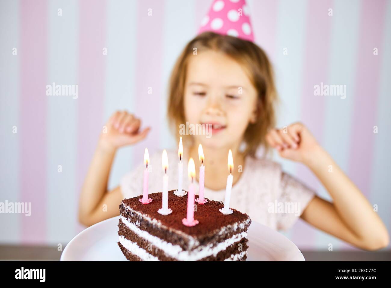 Little blonde girl smiling in birthday pink cap, a chocolate birthday ...