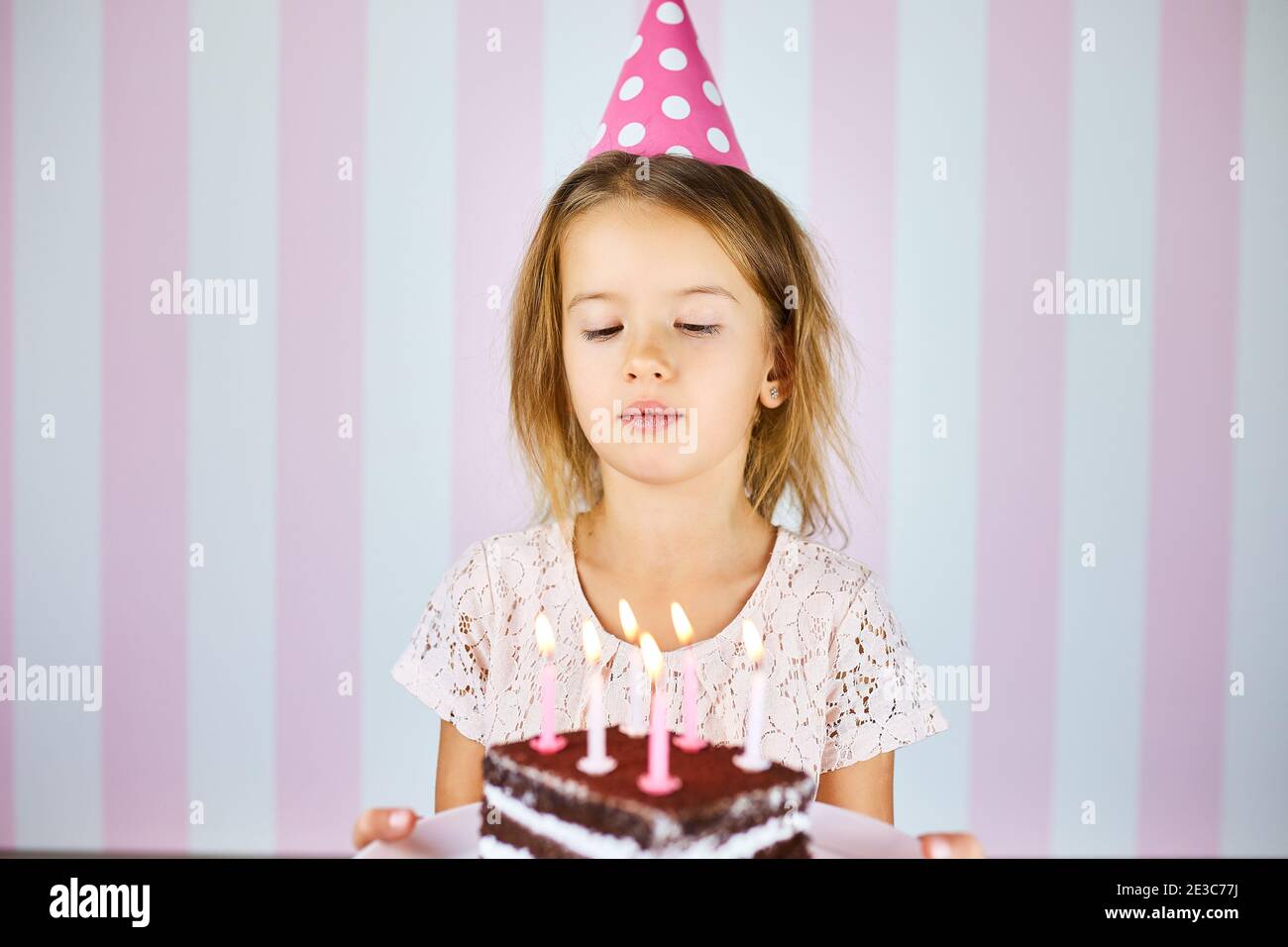 Little girl in pink birthday cap with 