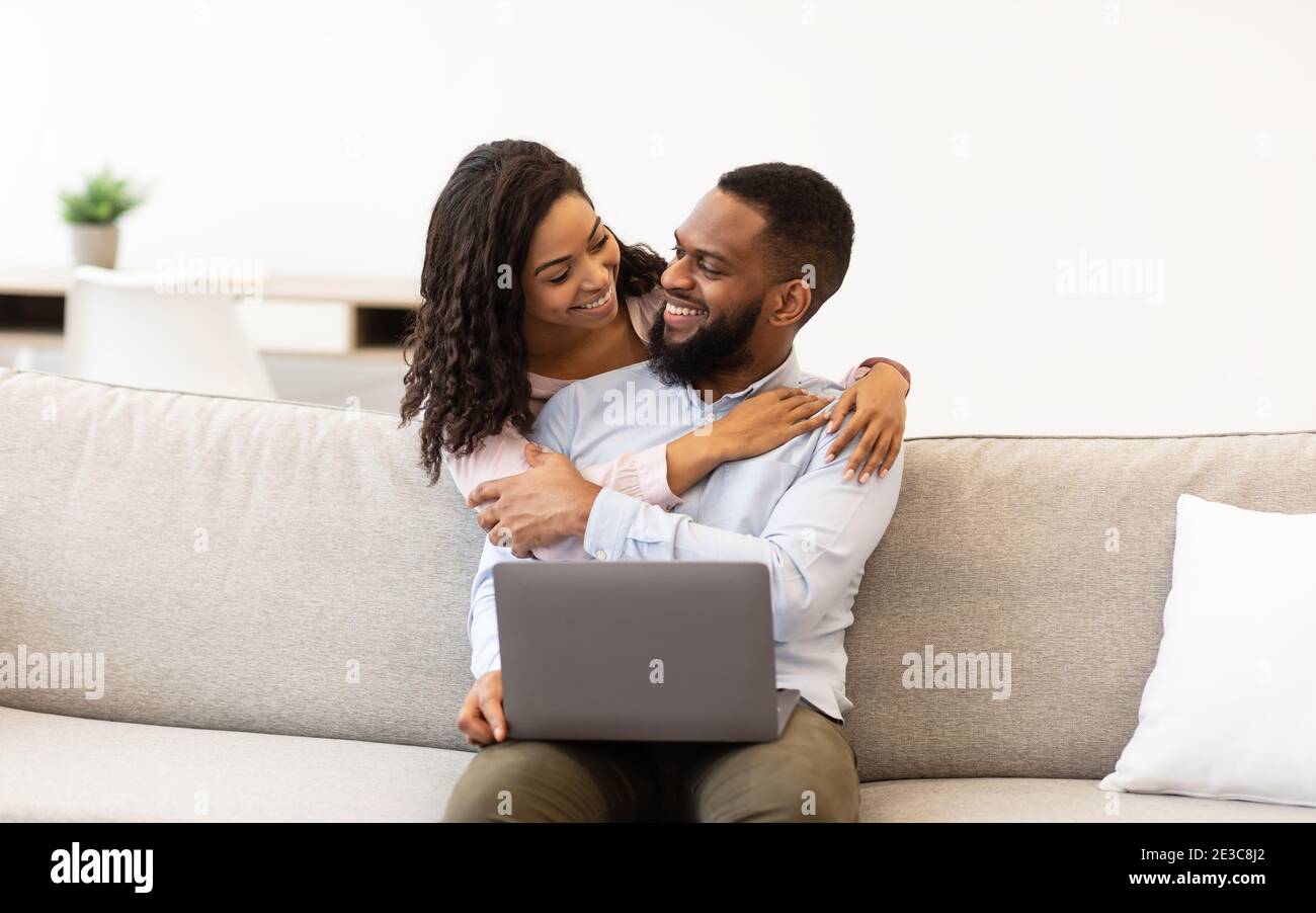Happy african american couple sitting on couch, using laptop Stock ...