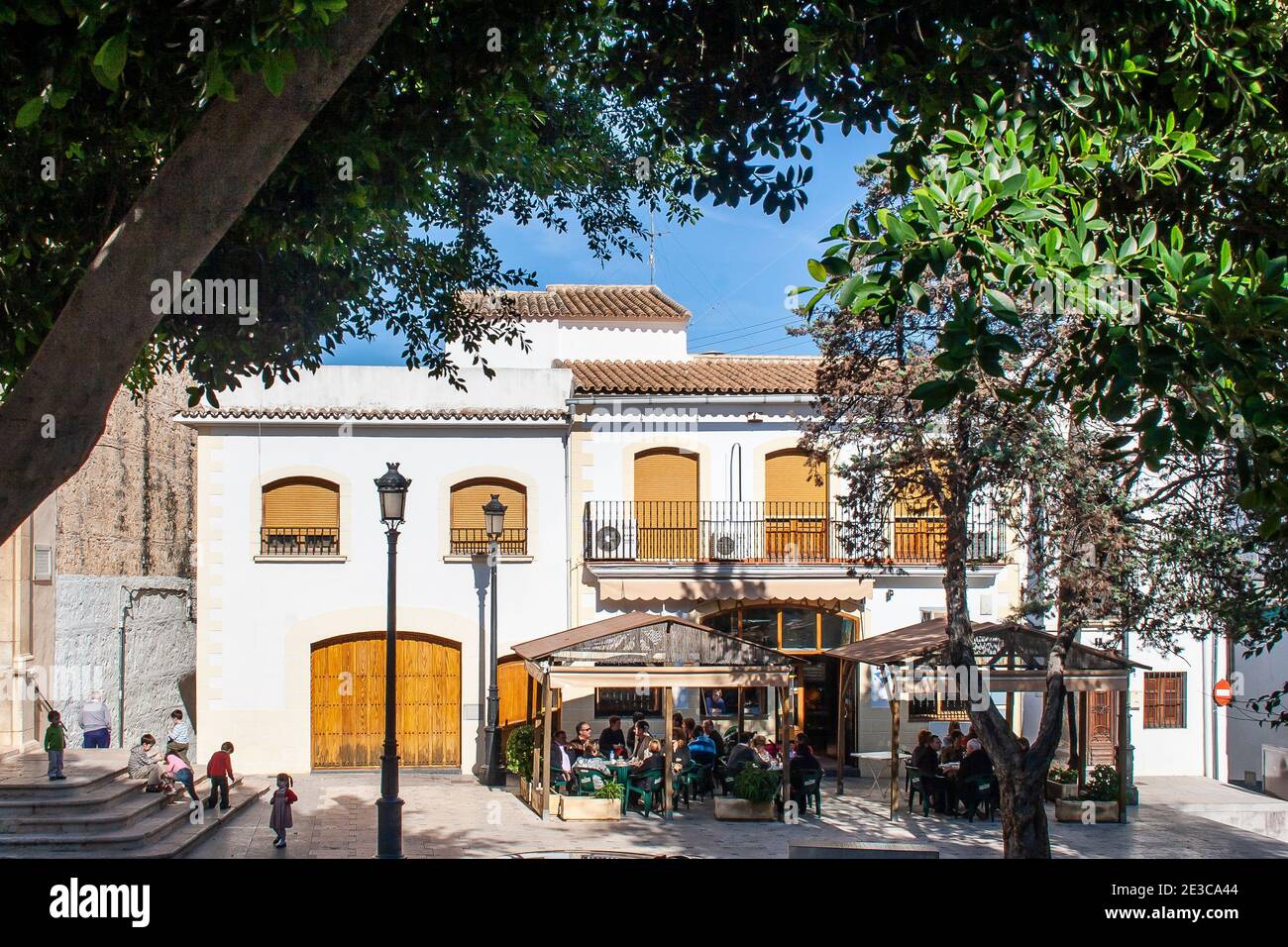 Chairs and tables set outside araditional Spanish bar in the church square on a sunny summer day at San Roc in Oliva in the Valencian region of Spain Stock Photo