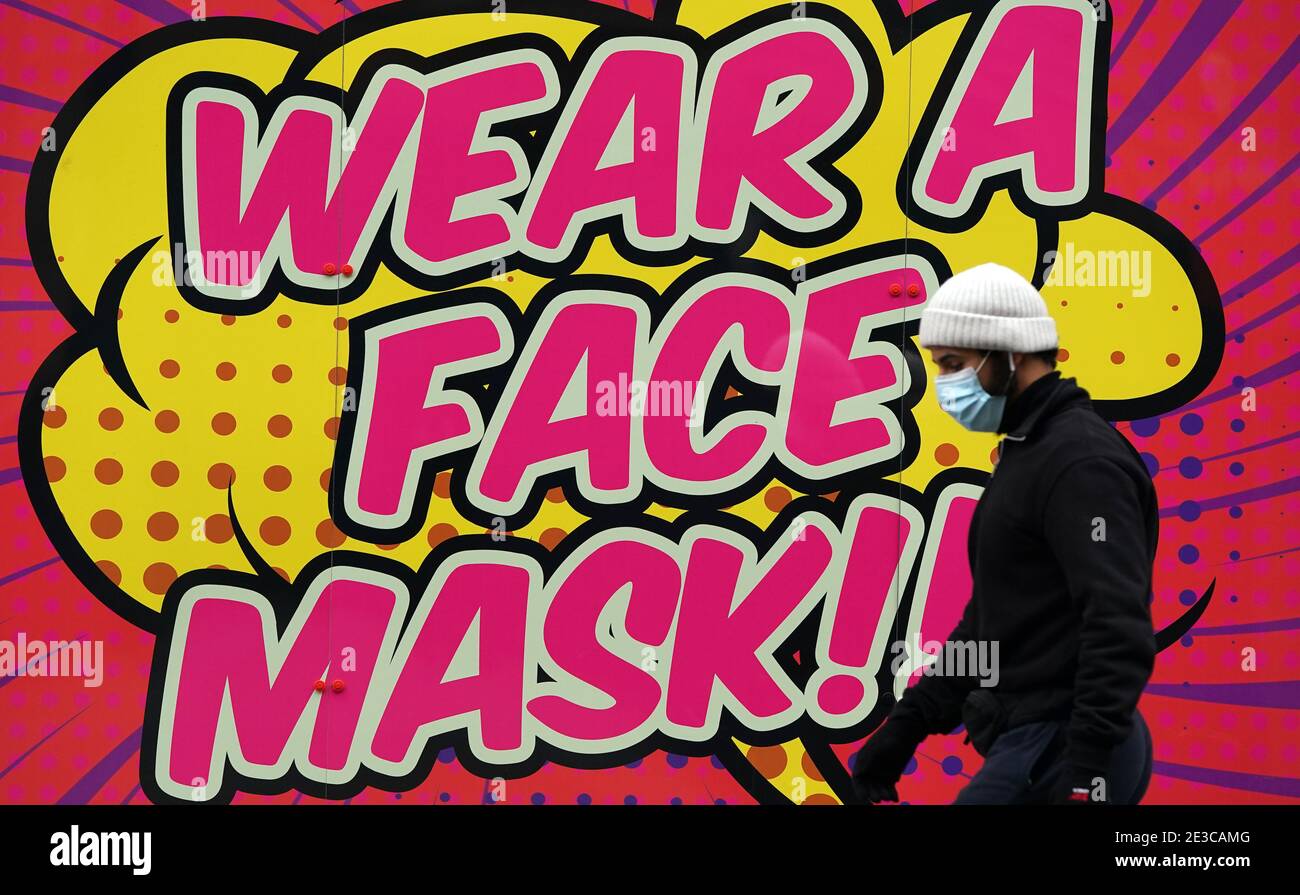 A person walks past a sign telling people to wear a face mask in Nottingham during England's third national lockdown to curb the spread of coronavirus. Picture date: Monday January 18, 2021. Stock Photo