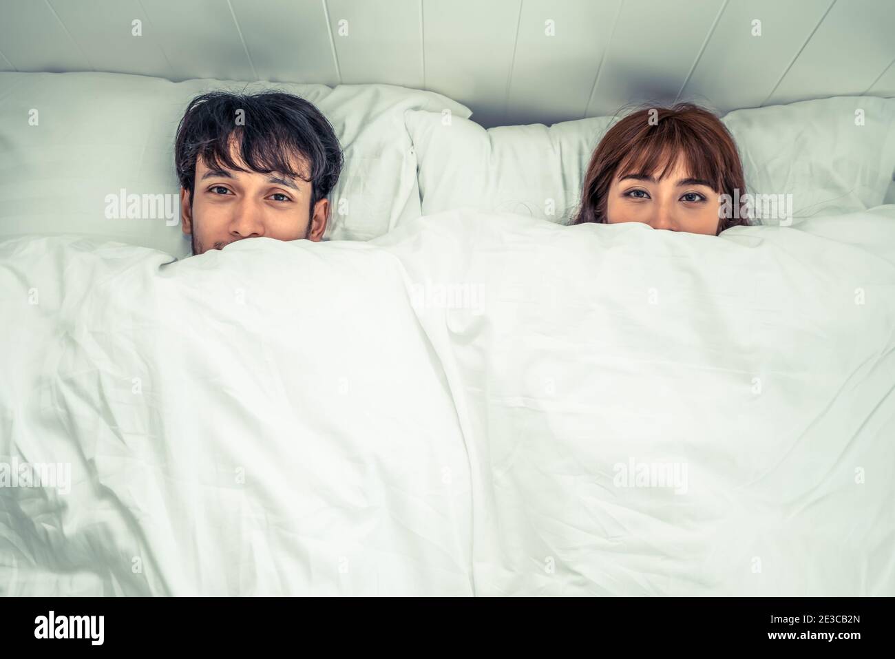 Happy young couple relaxing in home bedroom after waking up in the morning. Stock Photo