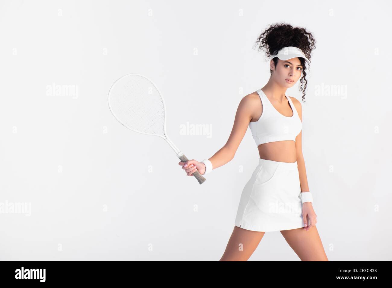 curly young player in sportswear holding tennis racket isolated on ...