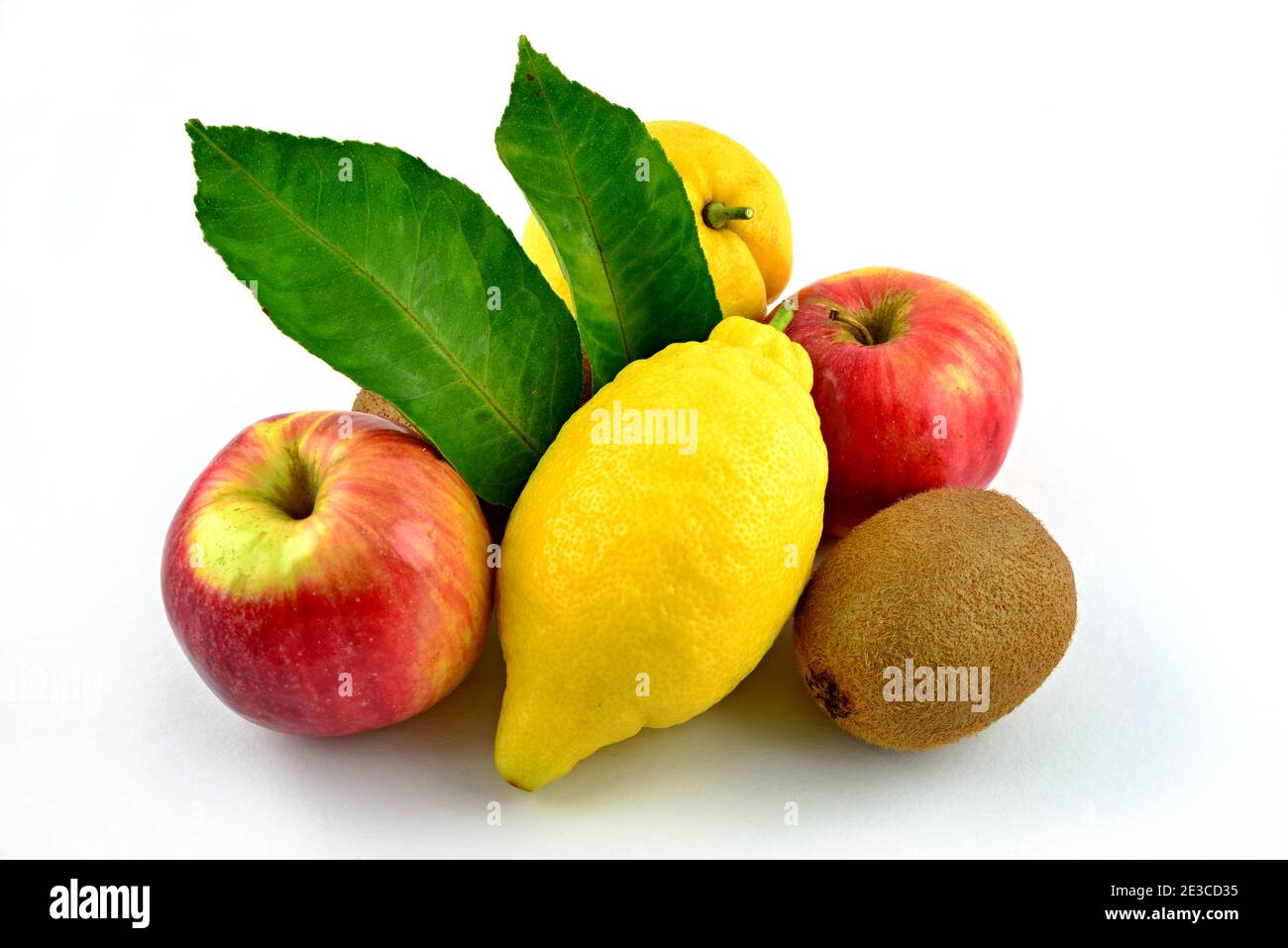 Mix of fruits, two yellow lemons, two red apples, one brown kiwi. Green lemon leaves. Stock Photo