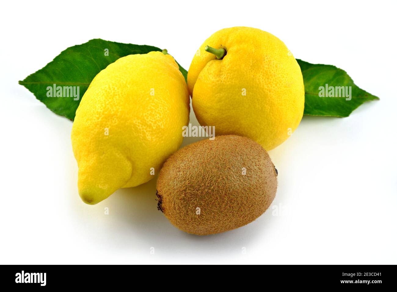 Mix of fruits, two yellow lemons, one brown kiwi. Green lemon leaves. Stock Photo