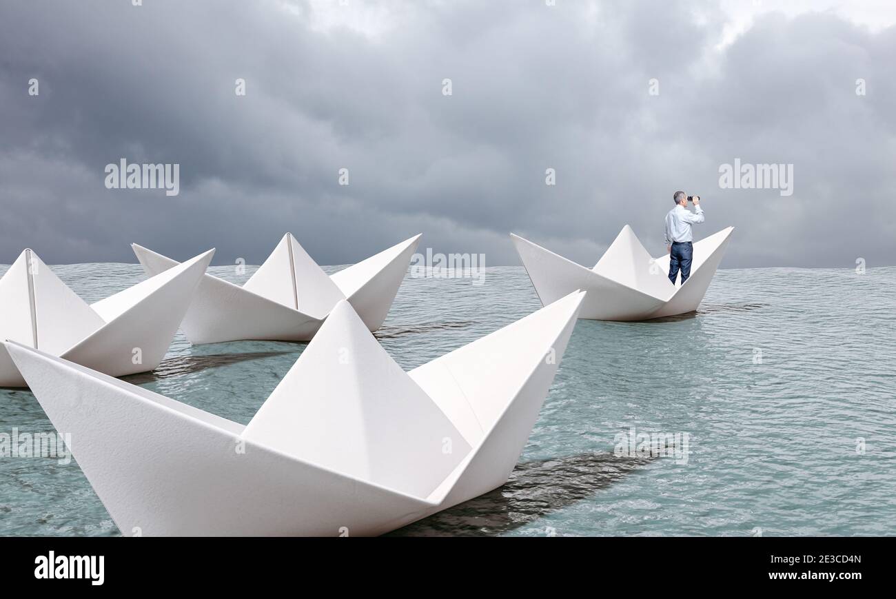 man on paper boat with binoculars sailing on the sea. Stock Photo