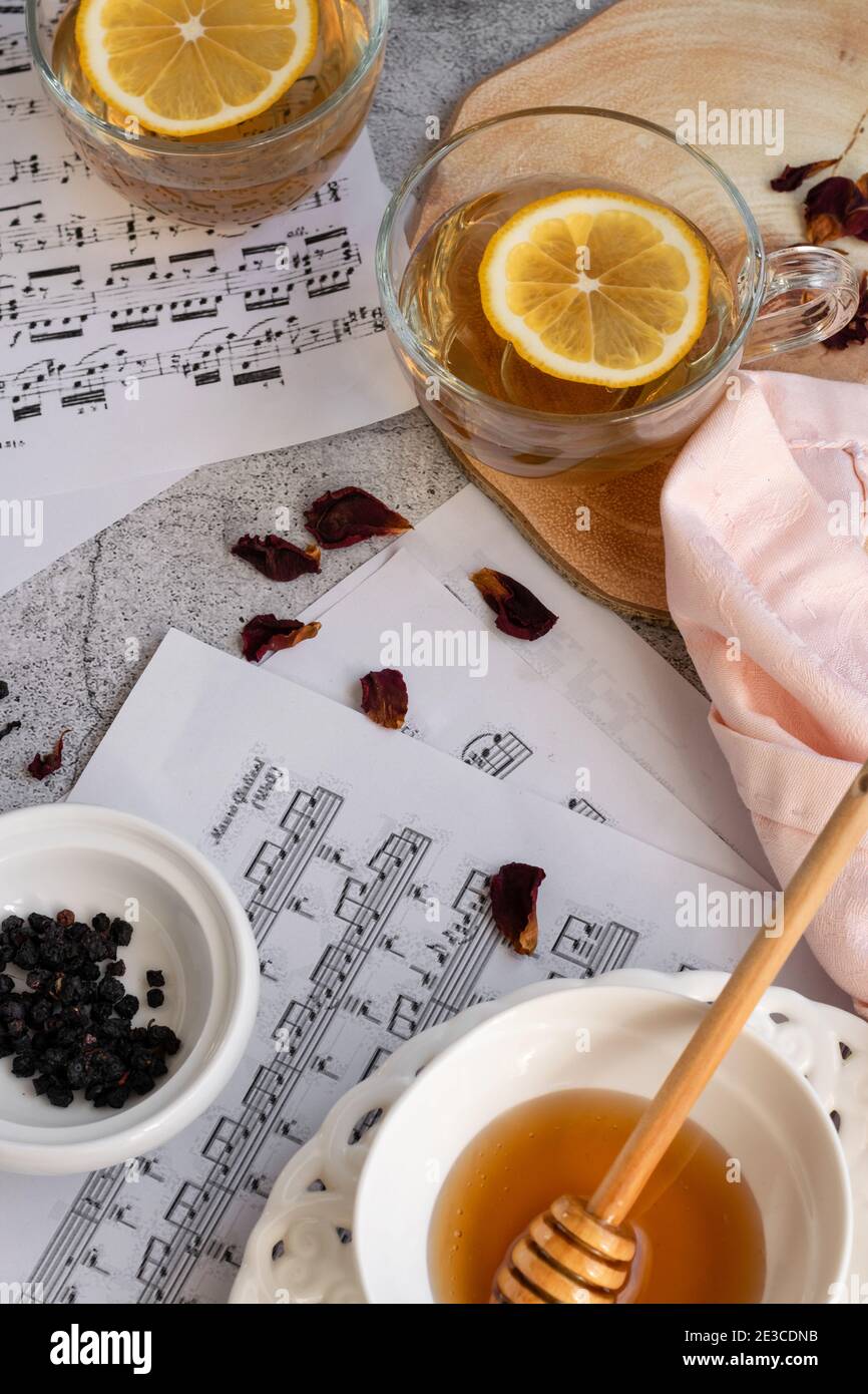 Cup of lemon tea and honey on grey background with music note sheets Stock Photo