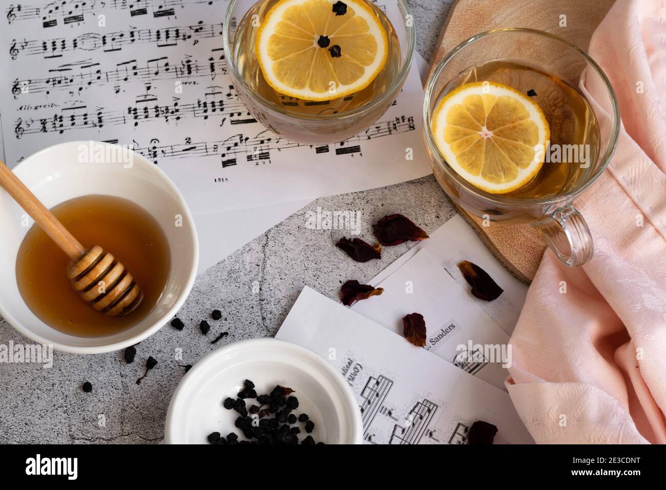 Cup of lemon tea and honey on grey background with music note sheets Stock Photo