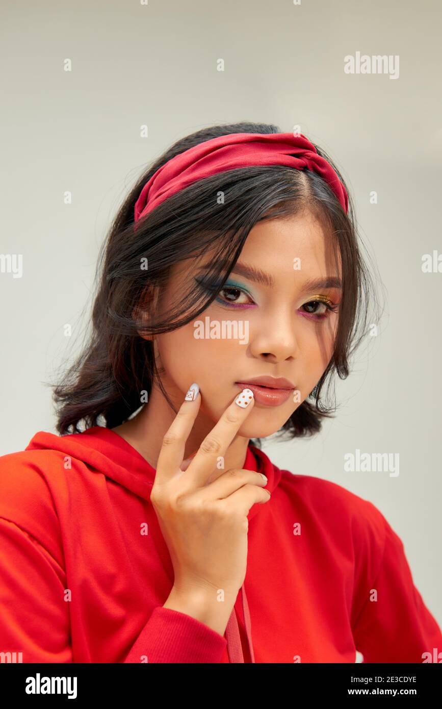 beautiful young woman with bright color make-up holding hands with bright manicure close to face Stock Photo