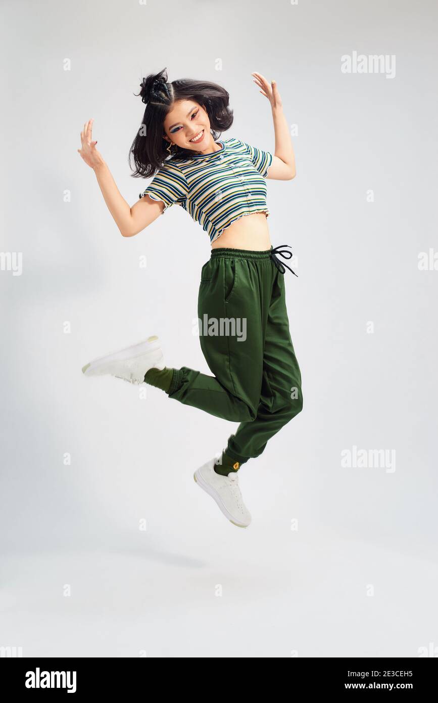 Portrait of cheerful positive girl jumping in the air with raised fists ...