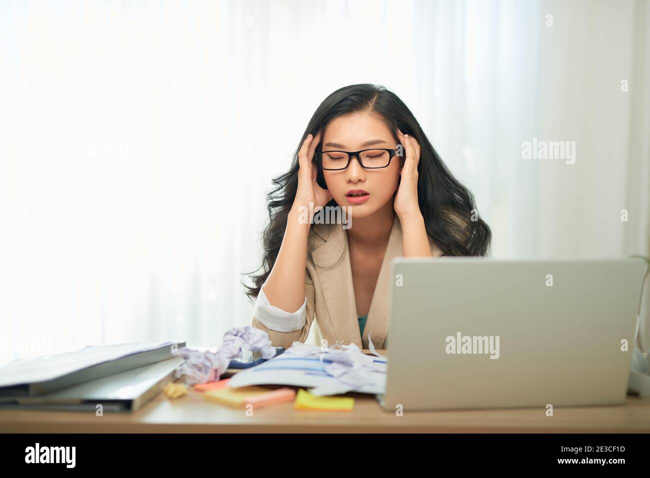 remote job, technology and people concept - stressed young woman with laptop computer and papers working at home office Stock Photo