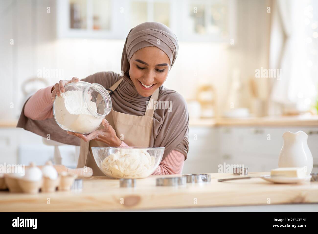 Happy muslim woman in hijab baking in kitchen, preparing dough for ...