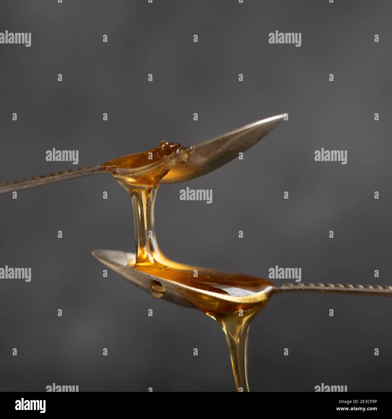 Spoons with raw honey bee on dark background, healthy nutrition concept