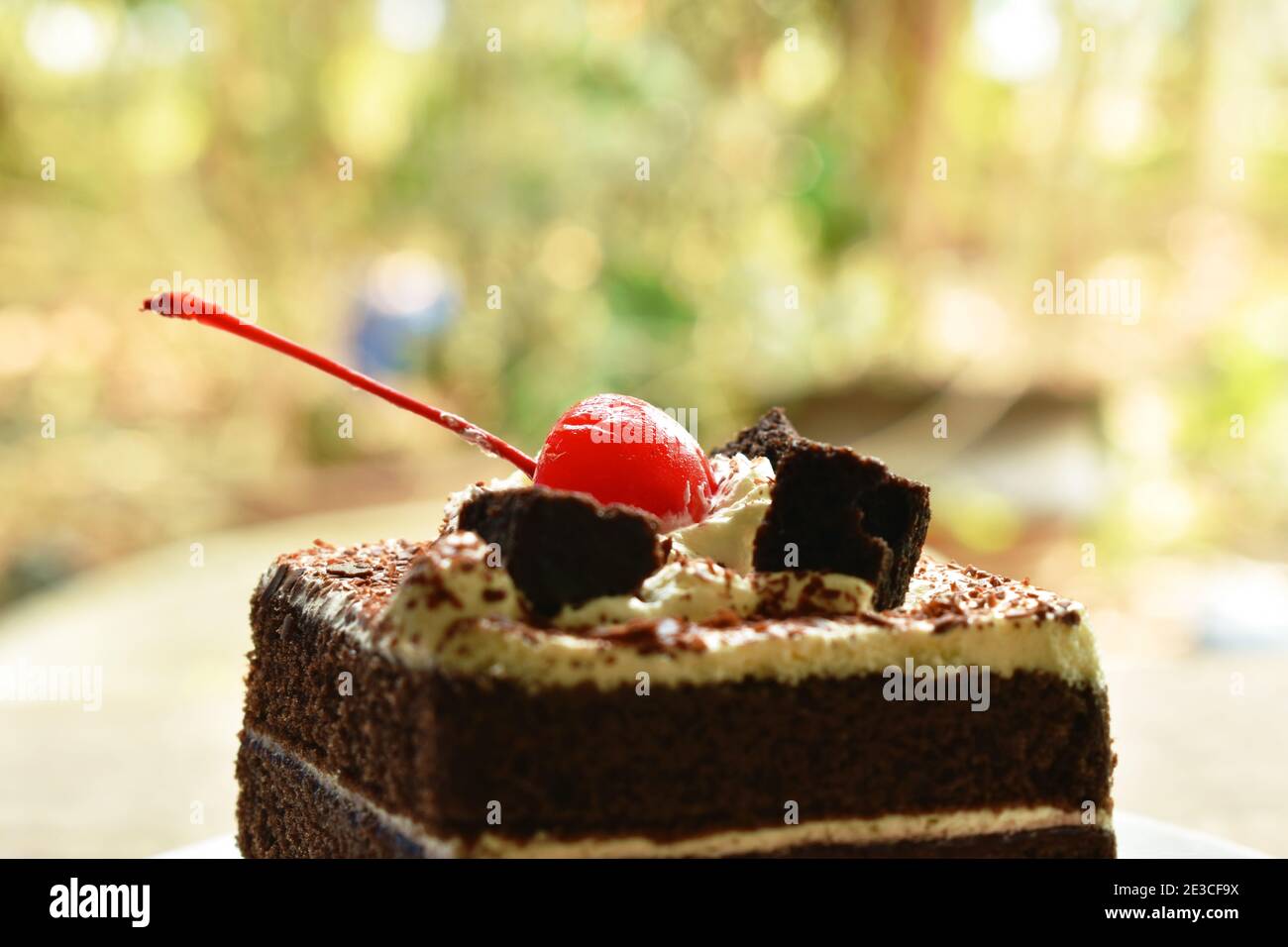black fotest cake with cream topping cherry on plate Stock Photo