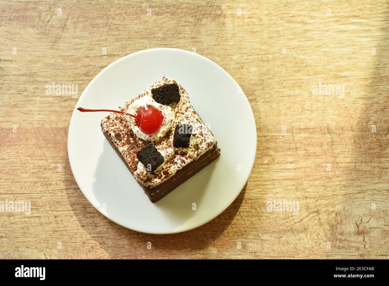 black fotest cake with cream topping cherry on plate Stock Photo