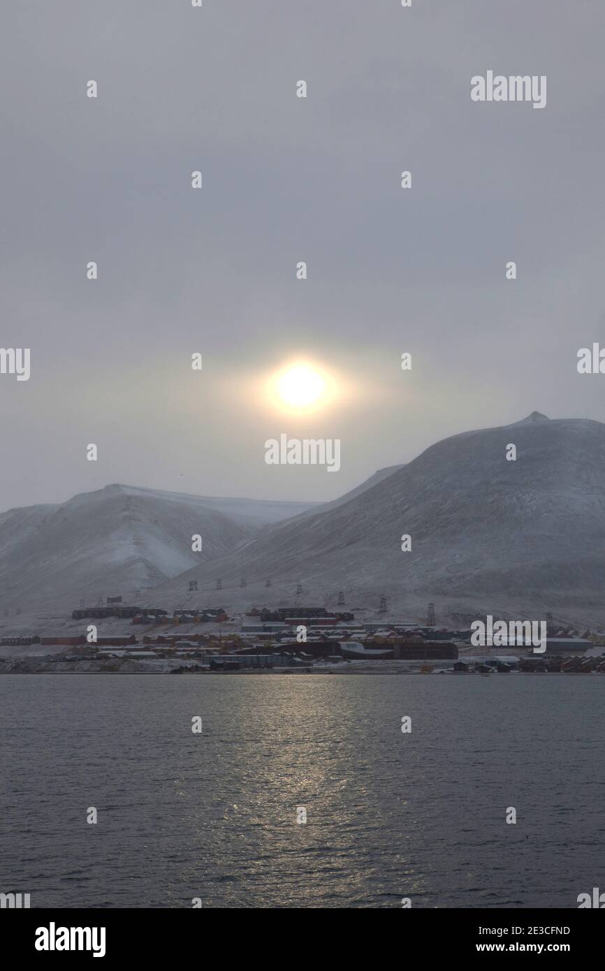 The sun pushes through a fog over the town of Longyearbyen, Svalbard. The northernmost settlement with more than 1,000 people on earth, and is quite w Stock Photo