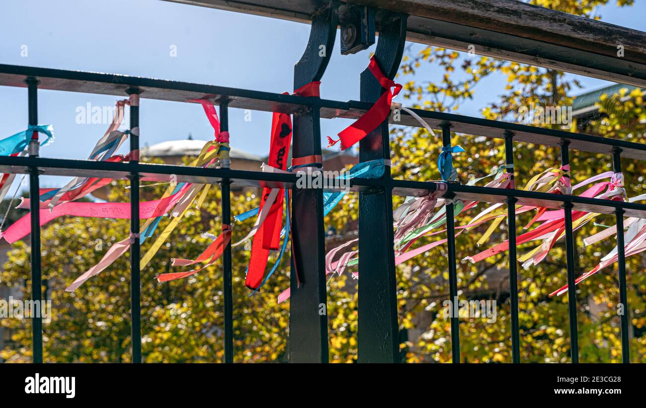 Coloured ribbons knotted to the river bridge, symbolising friendship and love written with messages en Portugal Stock Photo