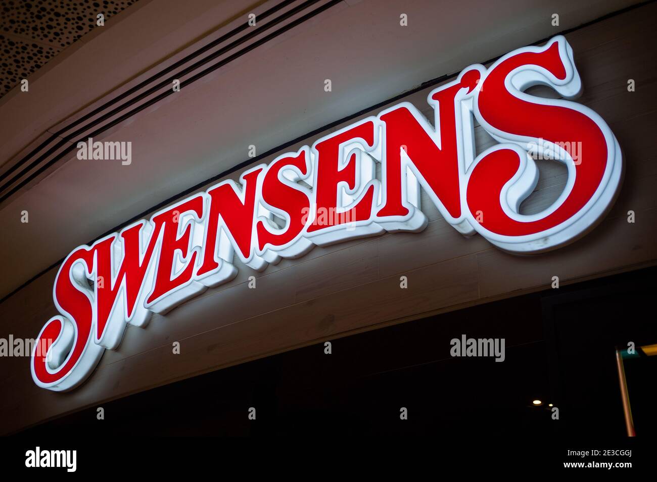 12.03.2020, Singapore, Republic of Singapore, Asia - Illuminated company sign with the lettering and logo of a Swensen's restaurant. Stock Photo