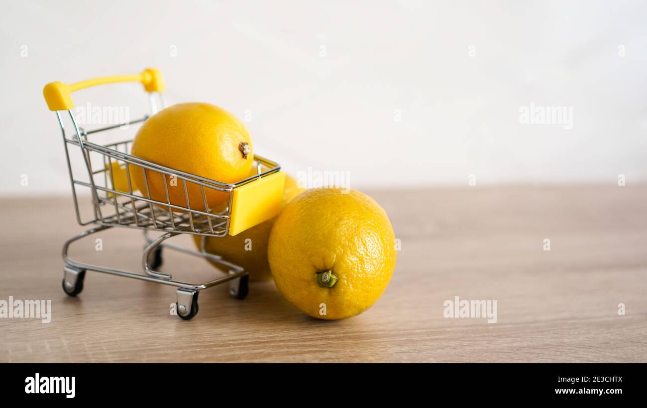 Lemon in a supermarket cart on kitchen table background. Two lemons by