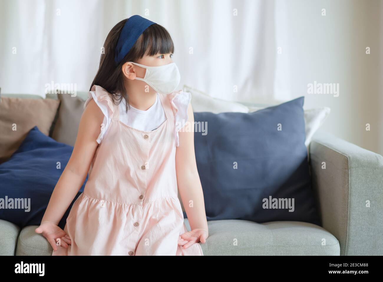 Asian little cute girl wearing hygienic face mask for prevent coronavirus or Covid-19 outbreak keep social distancing and stay at home. Stock Photo