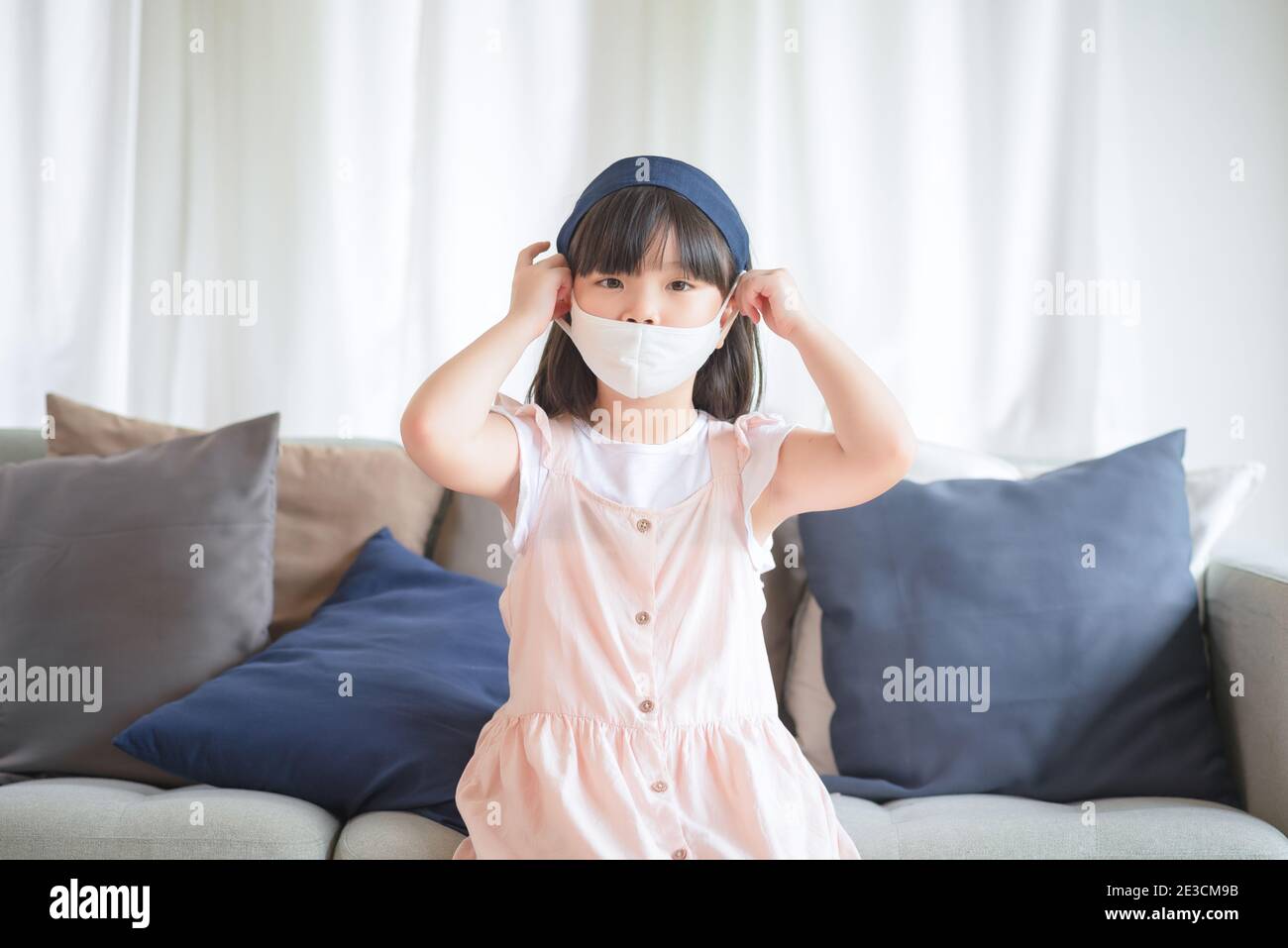 Asian little cute girl wearing hygienic face mask for prevent coronavirus or Covid-19 outbreak keep social distancing and stay at home. Stock Photo