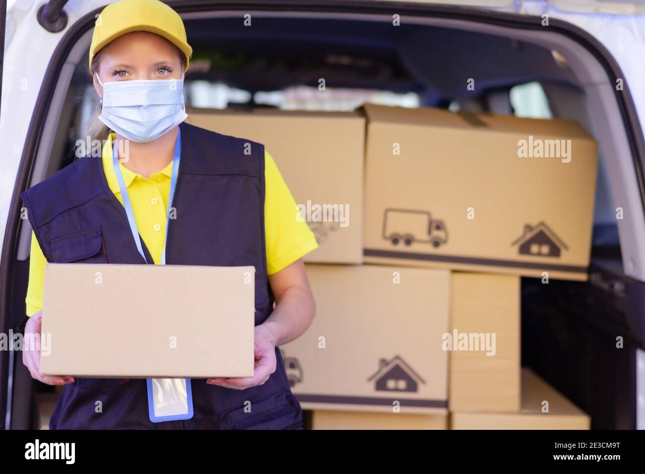 Portrait of delivery woman wearing face protective mask for coronavirus spread prevention. Covid 19 and buy concept. Stock Photo