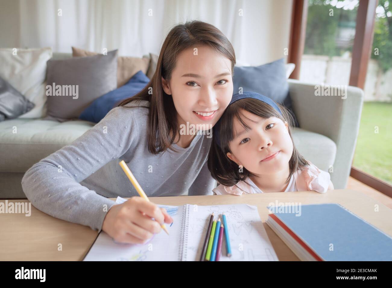 Happy asian mother teaching her cute kid daughter to studying preschool in living room at home Stock Photo