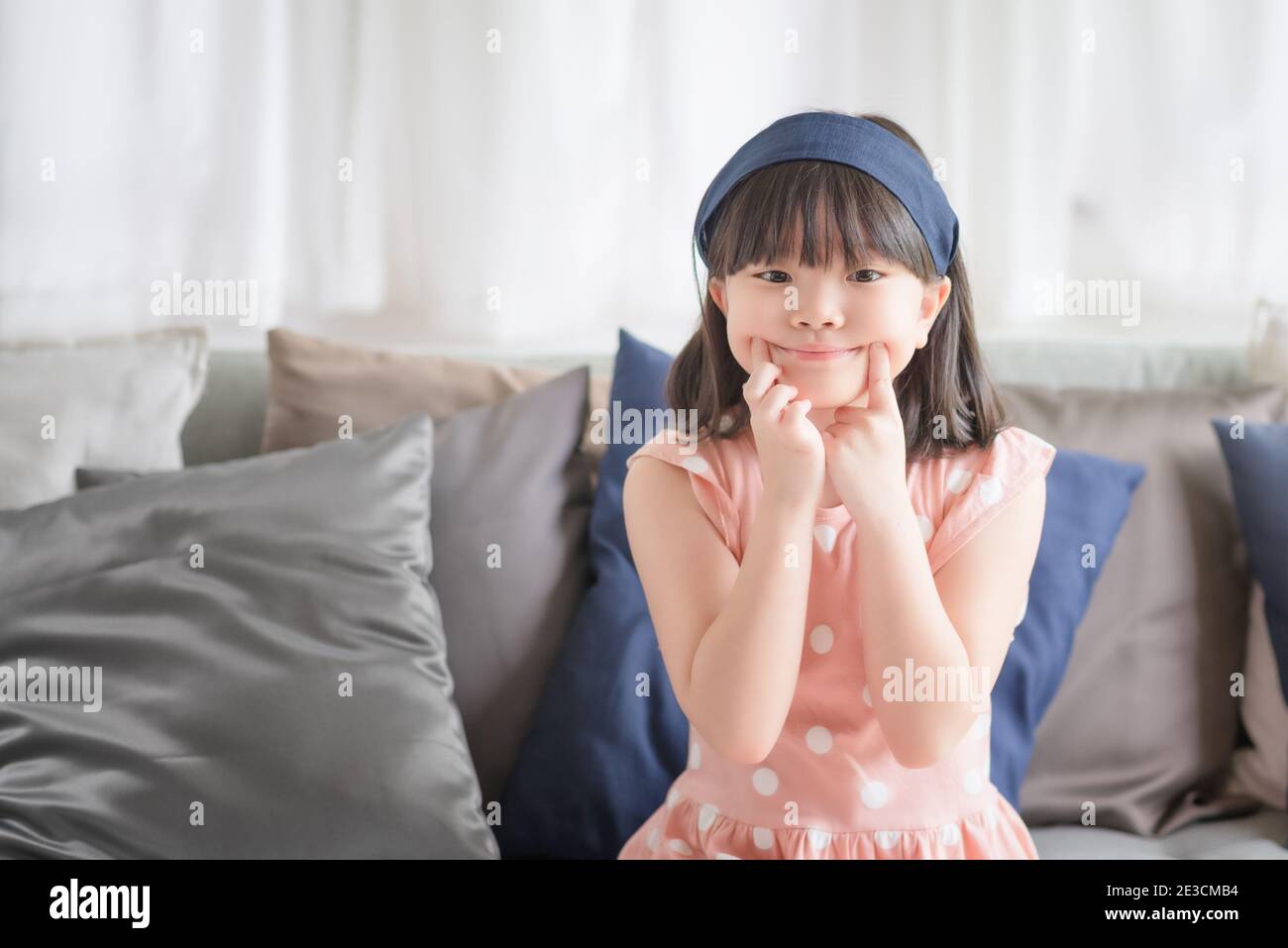 Portrait of asian little cute girl with happy charming smile in living room at home. Stock Photo