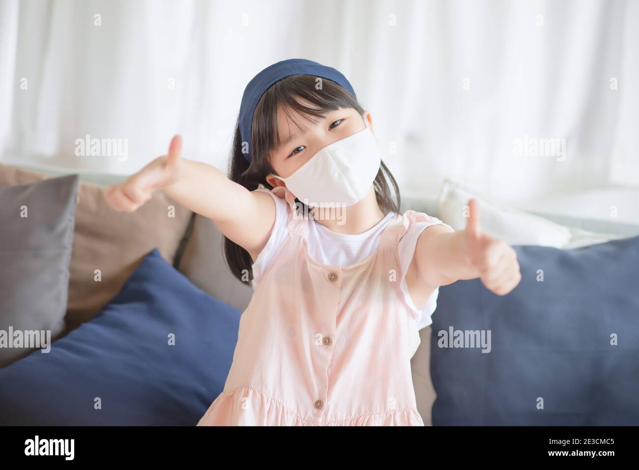 Asian little cute girl wearing hygienic face mask for prevent coronavirus or Covid-19 outbreak keep social distancing and stay at home. Stock Photo