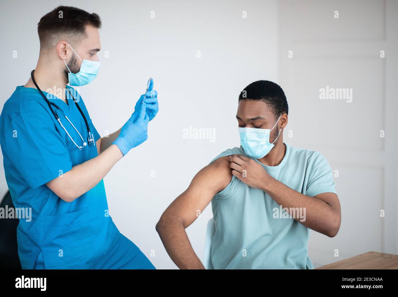 Covid-19 vaccination program. Black male patient getting coronavirus vaccine shot on visit to physician at health centre Stock Photo