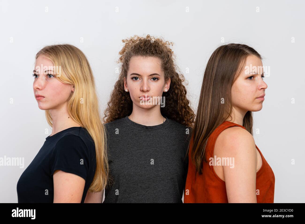 three sisters of different ages standing against each other, group ...