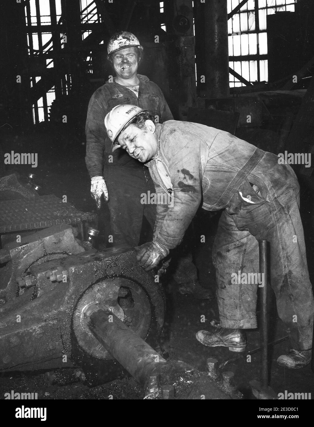 Two Laborers working in the Blue Coal's Huber Breaker. The Huber was a landmark located in the borough of Ashley, Hanover Township, Luzerne County, Pennsylvania, USA. The breaker was built in 1939 to replace the Maxwell Breaker which was located at the colliery. Run-of-mine coal arriving at the breaker was washed and cleaned to remove impurities, principally slate. It was crushed and screened to specific sizes desired by customers. Considered an ultra-modern plant when constructed. It processed 7,000 tons of Anthracite coal per day.The final product was sprayed with a blue dye and sold as “Blu Stock Photo