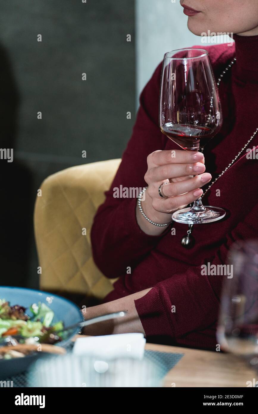 woman holds glass of red wine. people consider the color of the wine ...